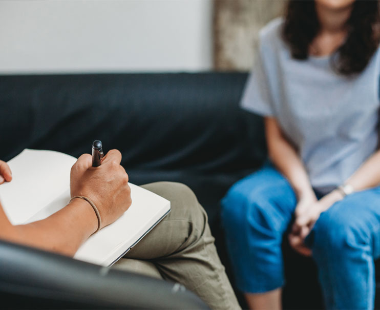 Therapist holding notebook while client speaks.